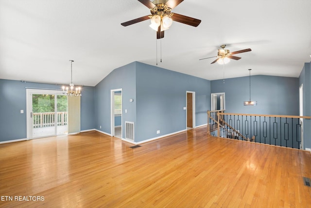 unfurnished room with ceiling fan with notable chandelier, vaulted ceiling, and hardwood / wood-style floors