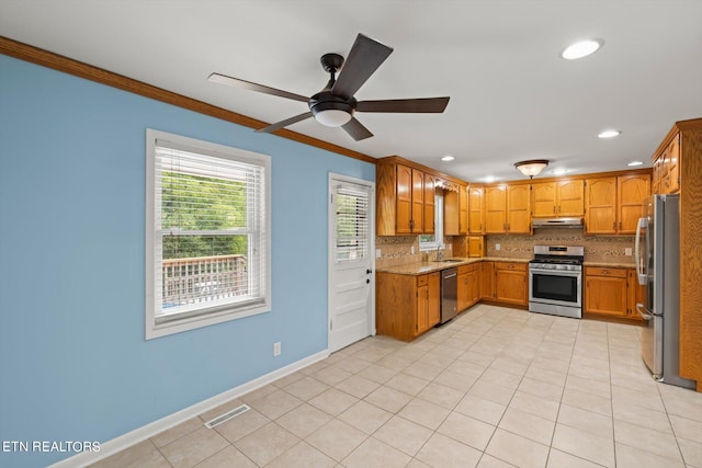 kitchen featuring stainless steel appliances, ornamental molding, ceiling fan, and tasteful backsplash