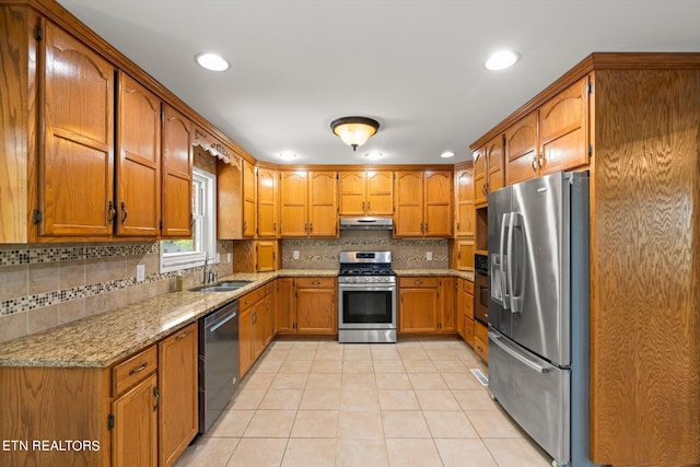 kitchen featuring light stone countertops, appliances with stainless steel finishes, sink, decorative backsplash, and light tile patterned flooring