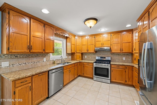 kitchen featuring light tile patterned floors, light stone countertops, stainless steel appliances, sink, and tasteful backsplash