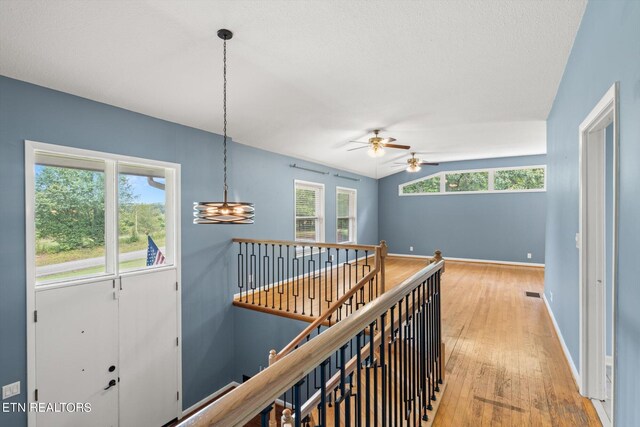 hallway with light wood-type flooring and vaulted ceiling