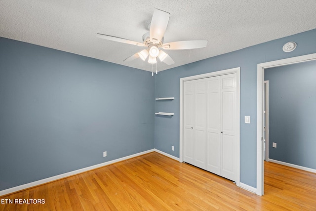 unfurnished bedroom with a closet, ceiling fan, light hardwood / wood-style floors, and a textured ceiling