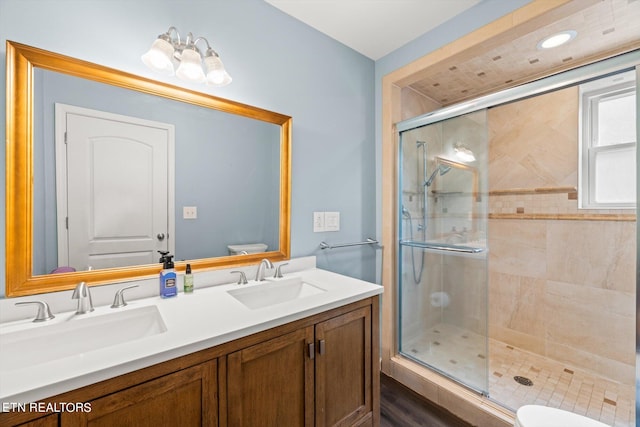 bathroom with vanity, toilet, wood-type flooring, and a shower with shower door