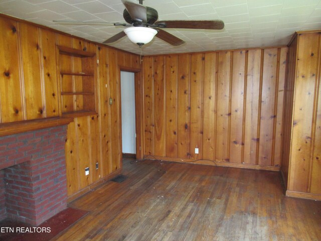 spare room featuring ceiling fan, dark hardwood / wood-style floors, and wooden walls