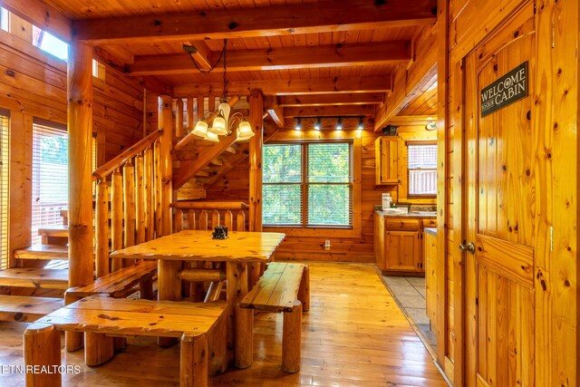 dining space with wood ceiling, beamed ceiling, wooden walls, and light hardwood / wood-style floors