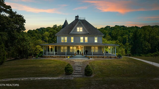 country-style home featuring covered porch and a lawn