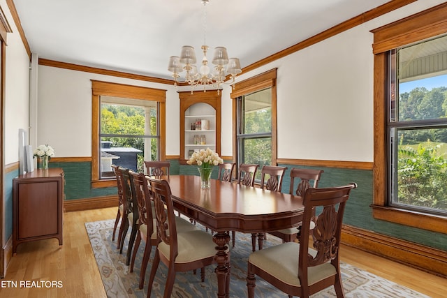 dining area with crown molding, a healthy amount of sunlight, light hardwood / wood-style flooring, and an inviting chandelier