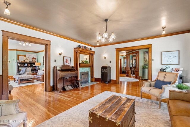 living room with ornamental molding, an inviting chandelier, and light hardwood / wood-style floors