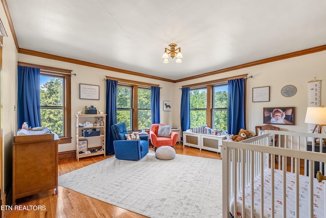 bedroom featuring hardwood / wood-style flooring, a nursery area, an inviting chandelier, and ornamental molding