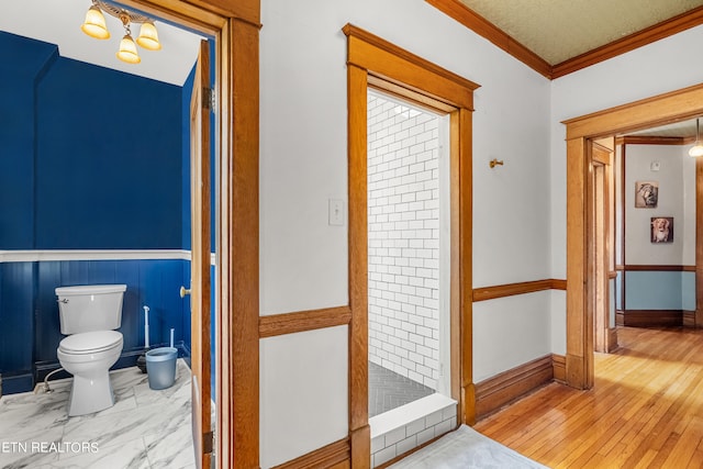 bathroom featuring hardwood / wood-style floors, toilet, crown molding, and a textured ceiling