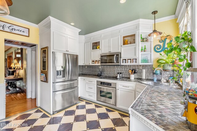 kitchen with ornamental molding, white cabinetry, sink, hanging light fixtures, and appliances with stainless steel finishes