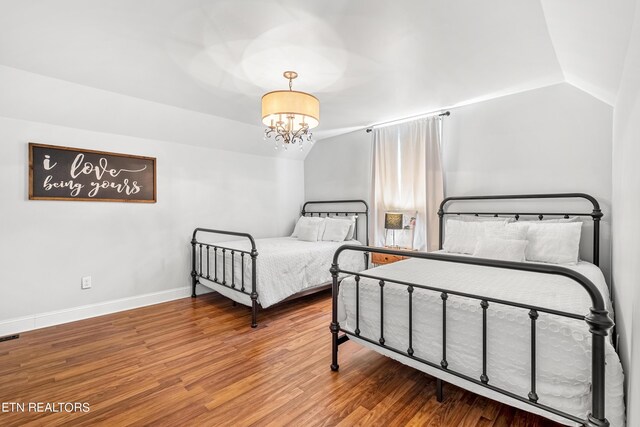 bedroom with vaulted ceiling, a notable chandelier, and hardwood / wood-style flooring