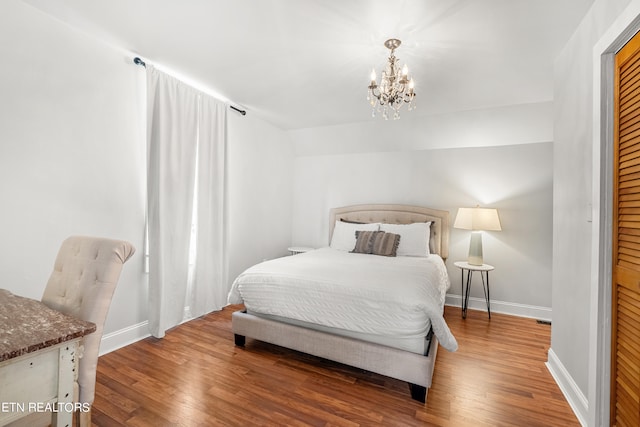 bedroom featuring hardwood / wood-style flooring, a chandelier, and vaulted ceiling