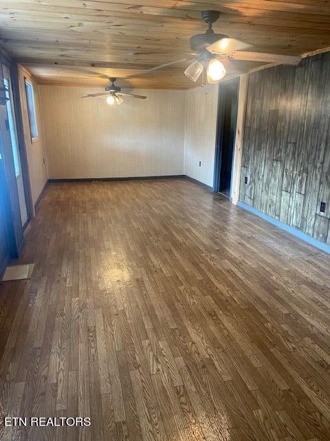 empty room with ceiling fan, dark hardwood / wood-style flooring, and wooden ceiling