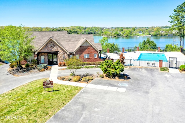 view of front of home featuring a fenced in pool and a water view