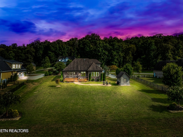 back house at dusk with a yard, a deck, and a shed