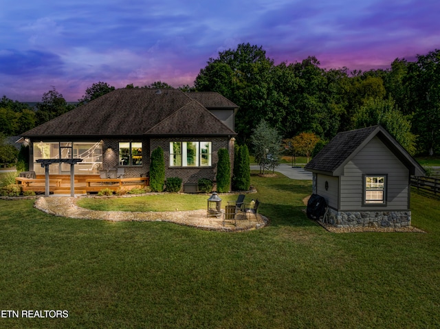 back house at dusk featuring an outbuilding and a yard