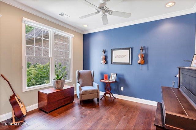 living area with dark wood-type flooring, ceiling fan, and crown molding