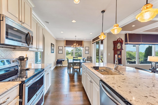 kitchen featuring pendant lighting, dark hardwood / wood-style flooring, light stone counters, sink, and appliances with stainless steel finishes