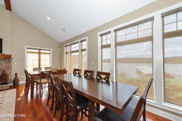 dining area with a fireplace, high vaulted ceiling, and wood-type flooring