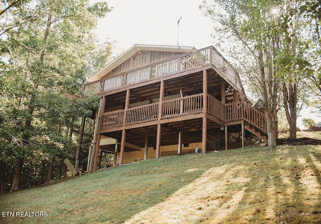 rear view of house featuring a lawn and a deck