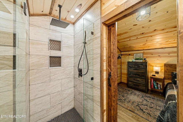 bathroom with a tile shower, wooden walls, vaulted ceiling, and wooden ceiling