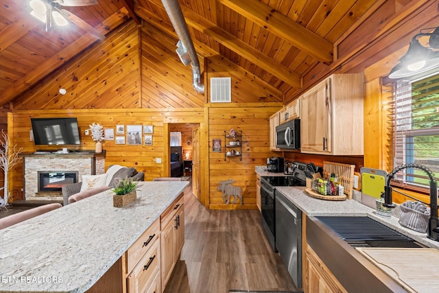 kitchen with dark hardwood / wood-style flooring, wood walls, stainless steel appliances, a stone fireplace, and ceiling fan