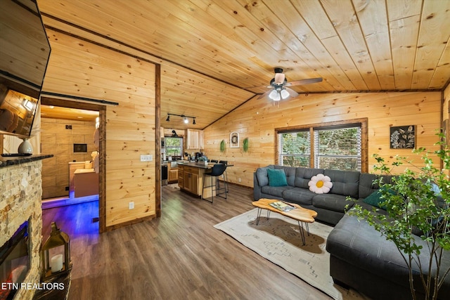 living room featuring dark wood-type flooring, a fireplace, wood walls, wooden ceiling, and lofted ceiling