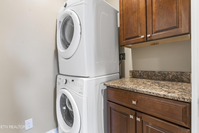 laundry room with cabinets and stacked washer / dryer