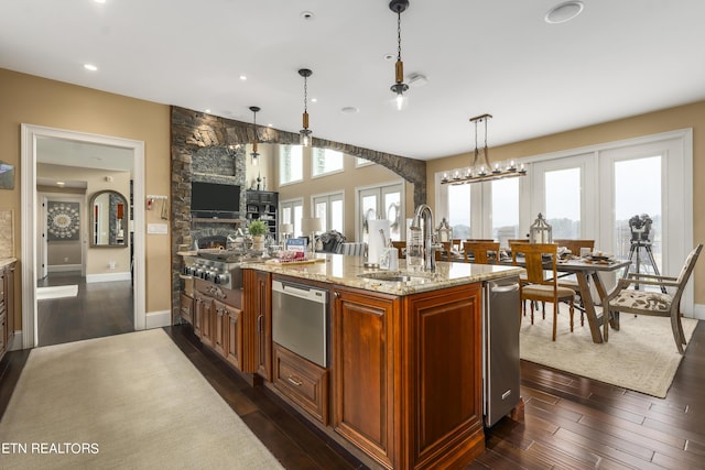 kitchen with light stone countertops, dark hardwood / wood-style flooring, a healthy amount of sunlight, sink, and pendant lighting