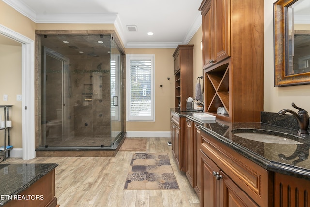 bathroom with hardwood / wood-style floors, vanity, ornamental molding, and walk in shower