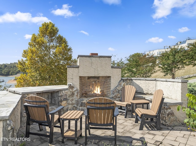 view of patio / terrace featuring an outdoor stone fireplace and a water view