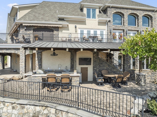 rear view of house featuring a balcony, exterior kitchen, and a patio