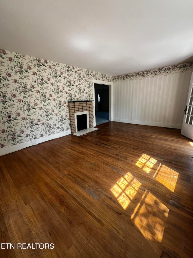 unfurnished living room featuring dark hardwood / wood-style flooring and a brick fireplace