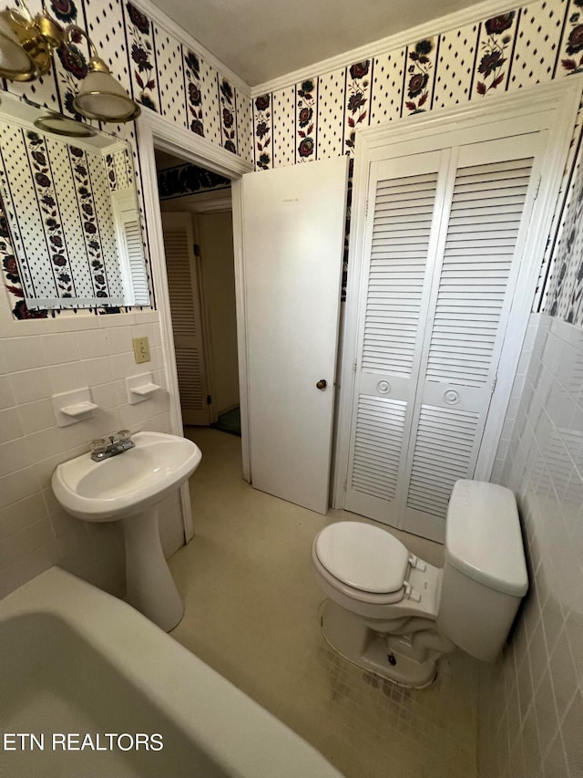 bathroom with a tub, toilet, and tile walls