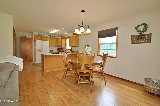 dining room with light wood-type flooring, a textured ceiling, and a chandelier