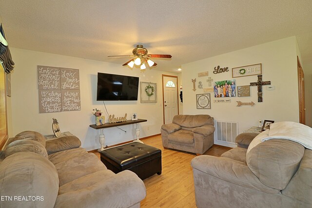 living room featuring light wood-type flooring, a textured ceiling, and ceiling fan