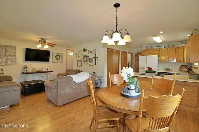 dining area with a textured ceiling, ceiling fan with notable chandelier, and light wood-type flooring