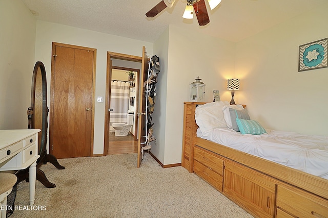 bedroom featuring a textured ceiling, baseboards, a ceiling fan, light carpet, and ensuite bath