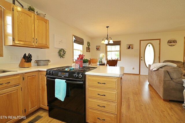 kitchen featuring black range, pendant lighting, kitchen peninsula, a chandelier, and light wood-type flooring