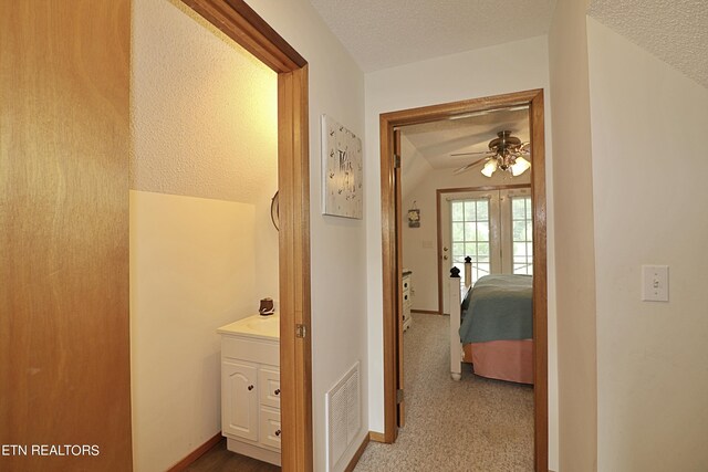 hallway featuring a textured ceiling, carpet floors, and lofted ceiling