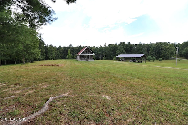 view of yard with a wooded view and a carport