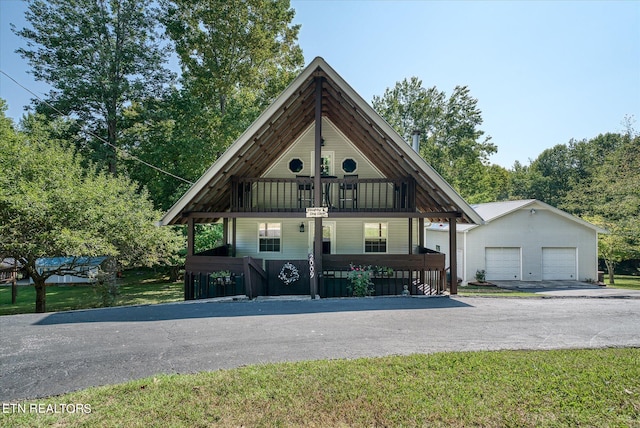 view of front of house featuring a front lawn, an outbuilding, a garage, and a porch