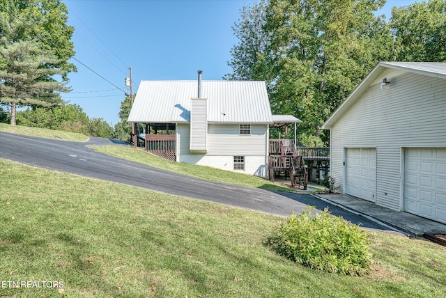 view of property exterior featuring a lawn, a garage, and a deck