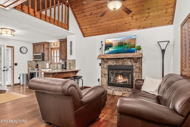 living room featuring a textured ceiling, vaulted ceiling, dark hardwood / wood-style floors, a fireplace, and ceiling fan