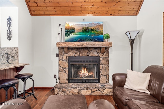 living room featuring lofted ceiling, hardwood / wood-style floors, wooden ceiling, and a stone fireplace