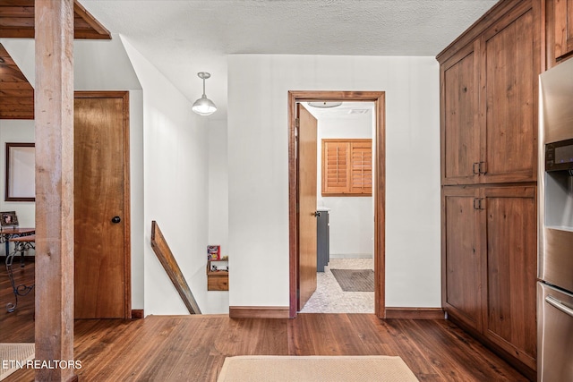 hallway with a textured ceiling and dark hardwood / wood-style flooring