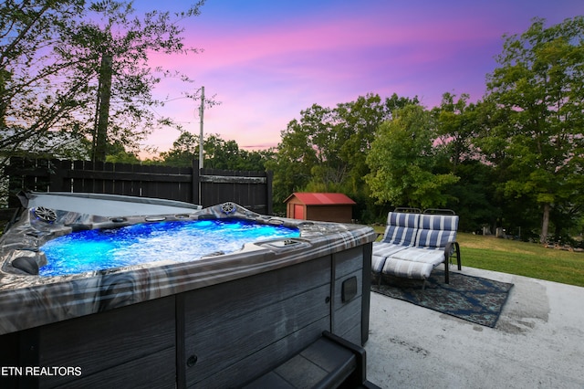 pool at dusk featuring a hot tub