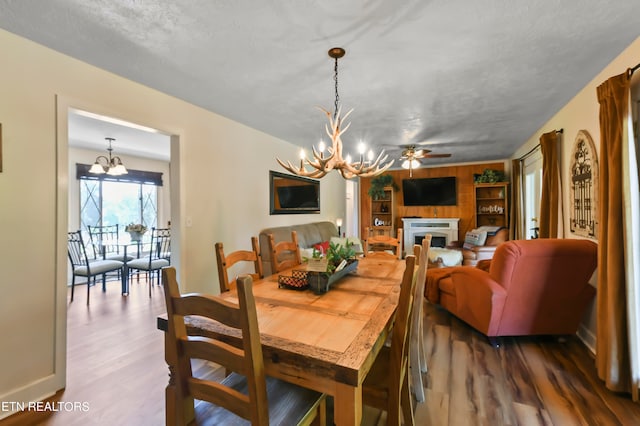 dining space featuring ceiling fan with notable chandelier, dark hardwood / wood-style flooring, and a textured ceiling