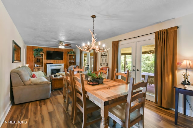 dining space featuring french doors, ceiling fan with notable chandelier, hardwood / wood-style flooring, and a textured ceiling